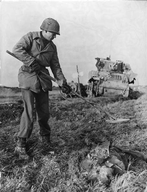 An American soldier uses a mine detector near the corpse ...
