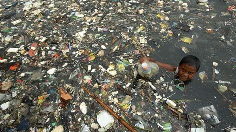Un niño recolecta plásticos en aguas contaminadas de la ...